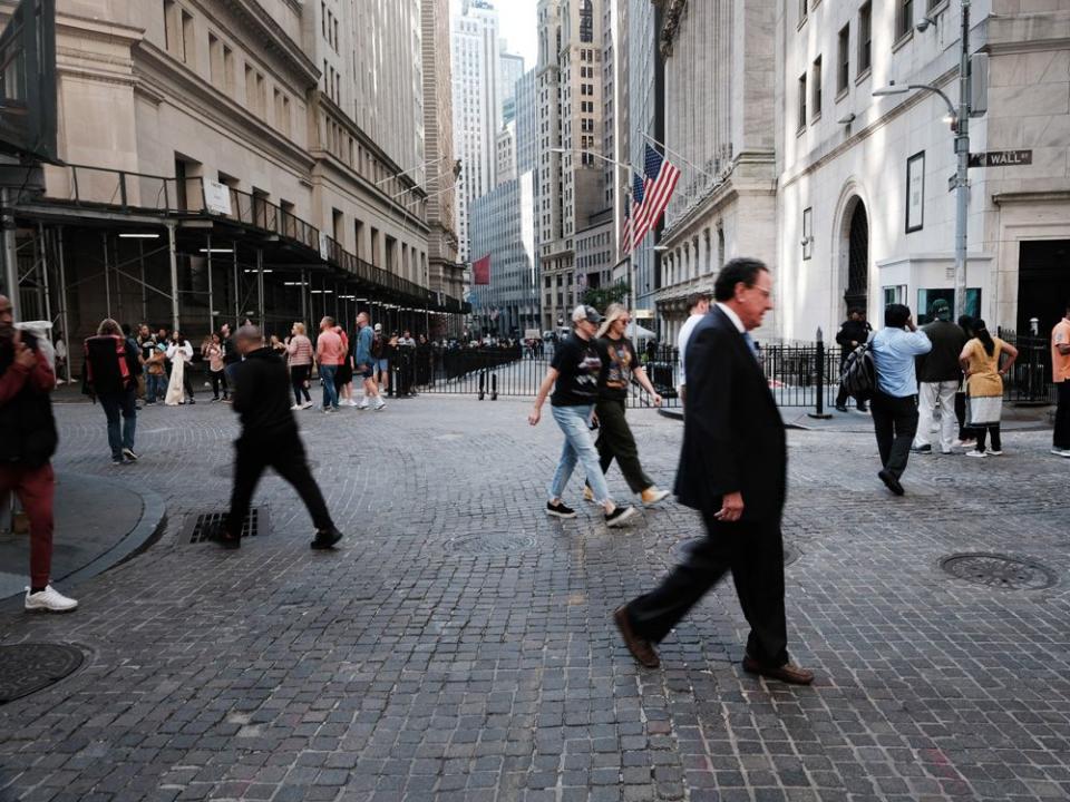  People walk along Wall Street by the New York Stock Exchange.