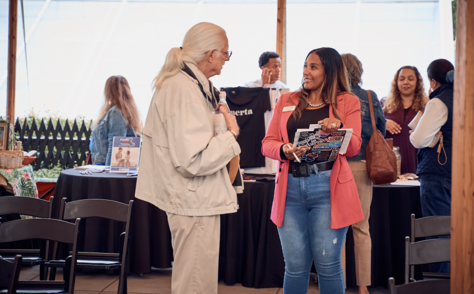 Samia Walker, right, welcomes a guest to the EforAll SouthCoast and BuyBlackNB Pitch Black on Thursday at the Rotch-Jones-Duff House.