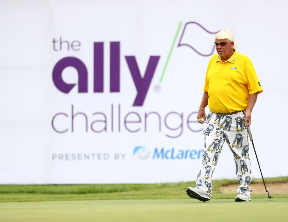 John Daly walks on the golf course in front of The Ally Challenge sign.