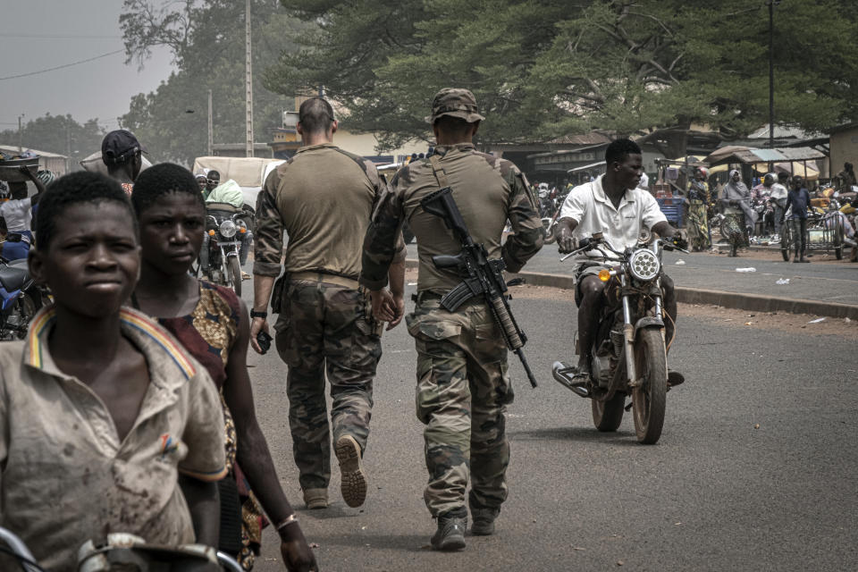 French army military instructors walk on one of the main roads in Tanguietan, northern Benin, March 28, 2022. Tanguietan, in the Atakora region of northern Benin bordering Burkina Faso, has suffered several jihadist attacks. Violence linked to al-Qaida and the Islamic State group, which has wracked much of West Africa's Sahel region for more than seven years is spreading into the coastal states and Benin has become the hardest hit. According to the Armed Conflict Location & Event Data Project, attacks have spiked more than tenfold. (AP Photo/ Marco Simoncelli)