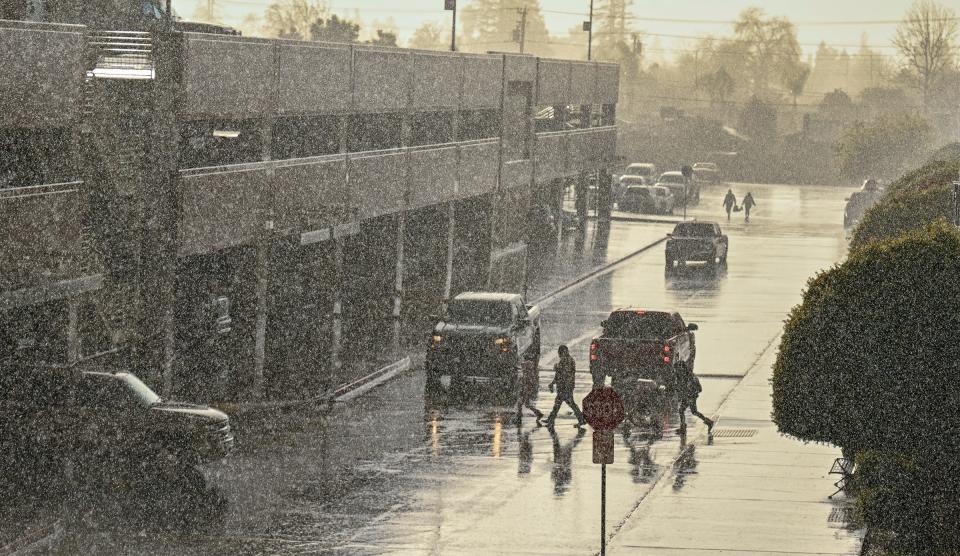 Pedestrians take in Sunday's rain at Visalia Mall. A double rainbow was visible later.