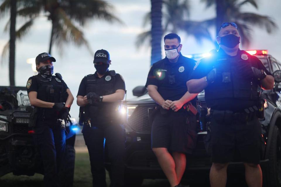 Miami Beach police officers keep an eye on people along Ocean Drive on March 19, 2021 in Miami Beach, Florida. A day later, police resorted to SWAT teams, military-style vehicles and pepper spray to enforce an 8 p.m. South Beach curfew announced only at 4 p.m.