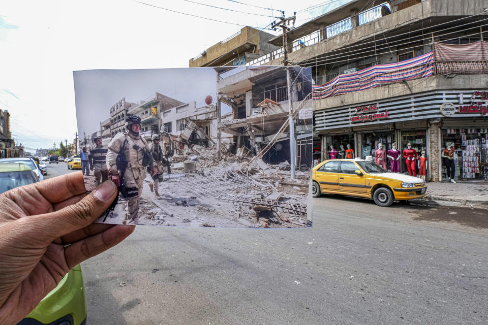 A photo of U.S. troops arriving at the site of a bomb blast in Baghdad's Camp Sara, a mainly Christian neighborhood, Wednesday, Oct. 4, 2006, is inserted into the scene at the same location on Tuesday, March21, 2023, 20 years after the U.S. led invasion on Iraq and subsequent war. (AP Photo/Hadi Mizban)