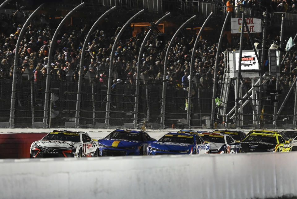 Denny Hamlin (11) leads a pack of cars to a restart during a NASCAR Cup Series auto race at Darlington Raceway, Sunday, Sept. 3, 2023, in Darlington, S.C. (AP Photo/Matt Kelley)