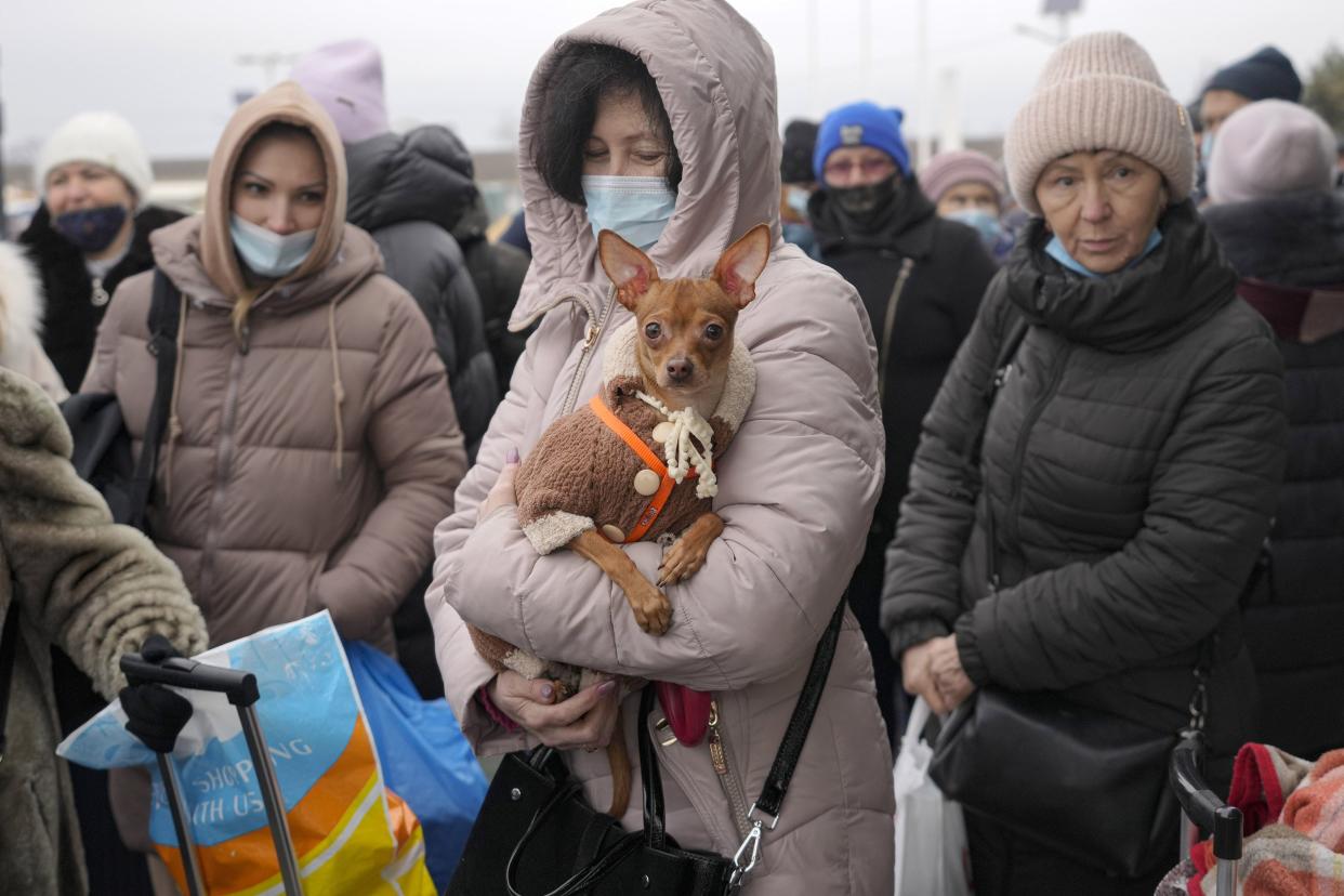 A woman holds her dog as she waits with others to cross from Ukrainian government controlled areas to pro-Russian separatists' controlled territory in Stanytsia Luhanska, the only crossing point open daily, in the Luhansk region, eastern Ukraine, Tuesday, Feb. 22, 2022. Russia says it's recognition of independence for areas in eastern Ukraine extends to territory currently held by Ukrainian forces. The statement Tuesday further raises the stakes amid Western fears that Moscow could follow up to Monday’s recognition of rebel regions with a full-fledged invasion of Ukraine.