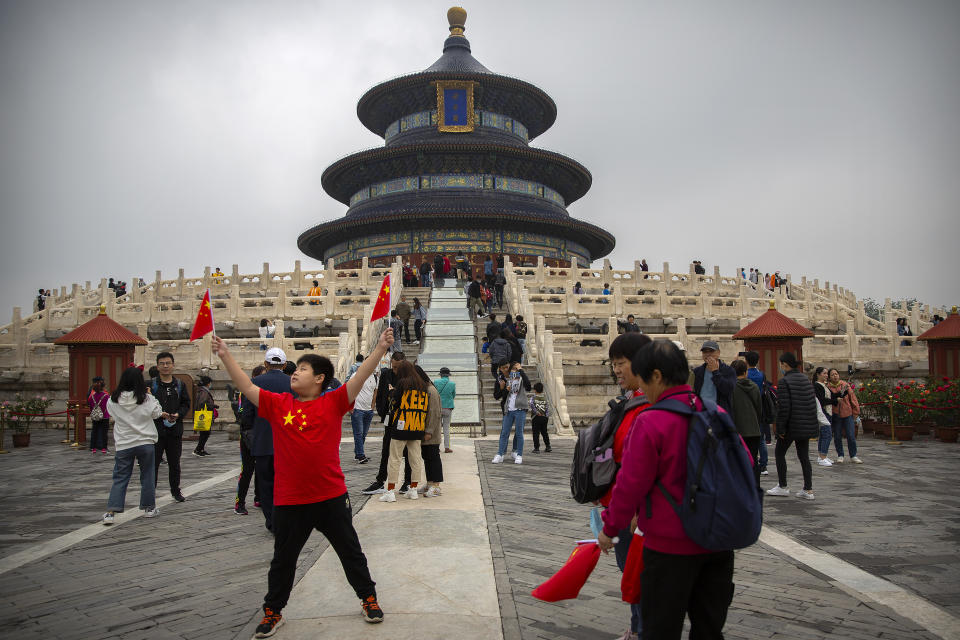 A boy poses with Chinese flags at the Temple of Heaven in Beijing, Thursday, Oct. 1, 2020. Millions of Chinese tourists usually would use their week-long National Day holidays to travel abroad. This year, travel restrictions due to the coronavirus pandemic mean that some 600 million tourists - about 40% of the population - will travel within China during the holiday that began Thursday, according to Ctrip, China's largest online travel agency. (AP Photo/Mark Schiefelbein)