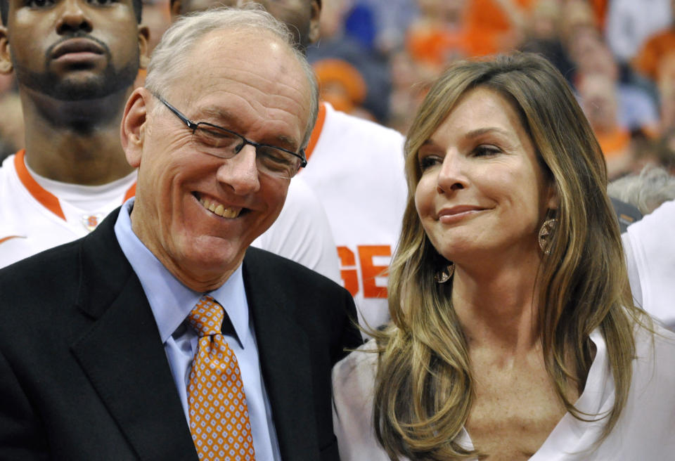 FILE - Syracuse coach Jim Boeheim smiles during a video tribute to his career, next to his wife, Julie, after Syracuse defeated Detroit 72-68 for his 900th win, at an NCAA college basketball game in Syracuse, N.Y., Monday, Dec. 17, 2012. Retirement is going just fine, thank you, for Jim Boeheim, who stepped down in March after 47 years of coaching the Orange. Juli Boeheim, his wife of 26 years, agreed and said he has “really unplugged well.”(AP Photo/Kevin Rivoli, File)