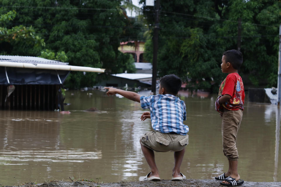 Children look at a flooded residential area near a river after the passing of Iota in La Lima, Honduras, Wednesday, Nov. 18, 2020. Iota flooded stretches of Honduras still underwater from Hurricane Eta, after it hit Nicaragua Monday evening as a Category 4 hurricane and weakened as it moved across Central America, dissipating over El Salvador early Wednesday. (AP Photo/Delmer Martinez)