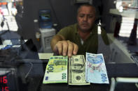 A currency exchange shop employee shows 100 Euros, 100 U.S. dollars and 100 Turkish Liras banknotes at his shop at a market street in Istanbul, Thursday, July 30, 2020. The Turkish Lira continued its trend down against the U.S. dollar Thursday but was still above a historic low in May. (AP Photo/Omer Kuscu)