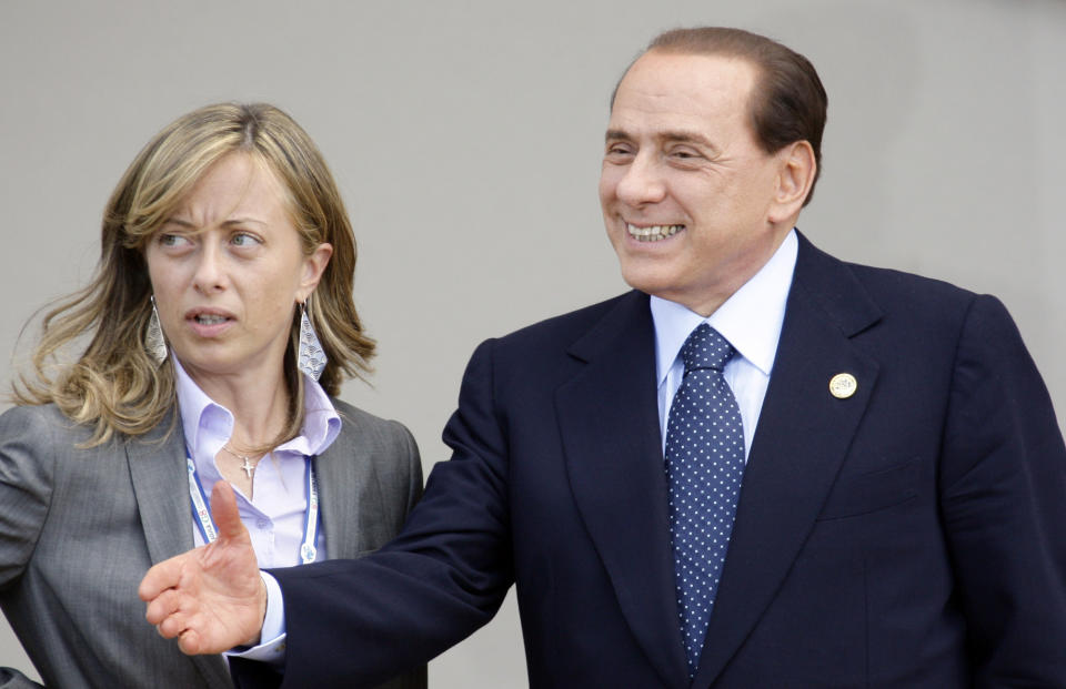 FILE — Italian Prime Minister Silvio Berlusconi, right, shares a word with Italian Minister for Youth Giorgia Meloni prior to a group photo of G8 and G5 leaders at the G8 summit in L'Aquila, Italy on Thursday, July 9, 2009. With God, homeland and "natural" family prominent in her political manifesto, Giorgia Meloni, whose Fratelli d'Italia (Brothers of Italy) party with neo-fascist roots has been fast rising in popularity in view of the upcoming Sept. 25 elections for Parliament, is positioning herself to become Italy's first far-right premier and the first woman to hold that office. (AP Photo/Stefano Rellandini, Pool)