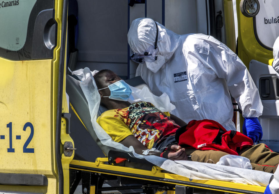 A migrant is taken on a stretcher by medical workers as he arrives with others migrants at the Arguineguin port in Gran Canaria island, Spain, after being rescued in the Atlantic Ocean by emergency workers on Tuesday, Oct.20, 2020. Some 1,000 migrants have spent the night again sleeping in emergency tents in a dock while authorities in the Canary Islands complain that the Spanish government keeps blocking transfers of newly arrived migrants to the mainland over coronavirus concerns. (AP Photo/Javier Bauluz)