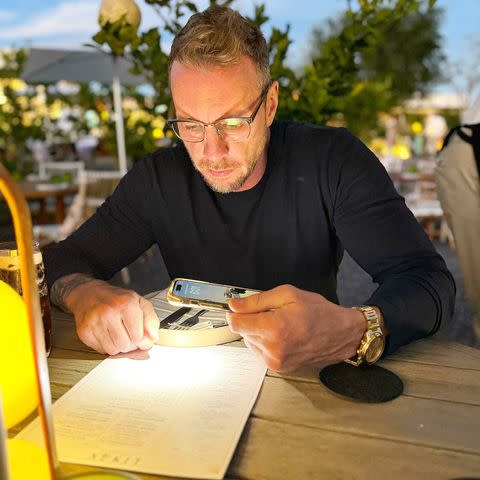<p>Kristen Bell/Instagram</p> Shepard using his flashlight to look at the menu