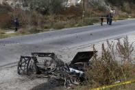 Police guard the perimeter of a burned-out car outside the Tula General Hospital, after a gang rammed several vehicles into a prison and escaped with nine inmates, in Tula, Mexico, Wednesday, Dec. 1, 2021. Local media reported that the burned-out cars found in the city after the attack were car bombs. Authorities said they were investigating how the vehicles caught fire. (AP Photo/Ginnette Riquelme)