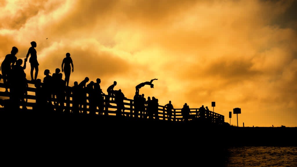 Silhouettes of people jumping off of the “Jaws” bridge on Beach Road in Martha’s Vineyard. (Adobe Stock)