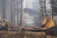 A cabin partially covered in fire-resistant material stands behind a property destroyed in the Caldor Fire in Twin Bridges, Calif., Thursday, Sept. 2, 2021. Better weather on Thursday helped the battle against a huge California forest fire threatening communities around Lake Tahoe, but commanders warned firefighters to keep their guard up against continuing dangers. (AP Photo/Jae C. Hong)