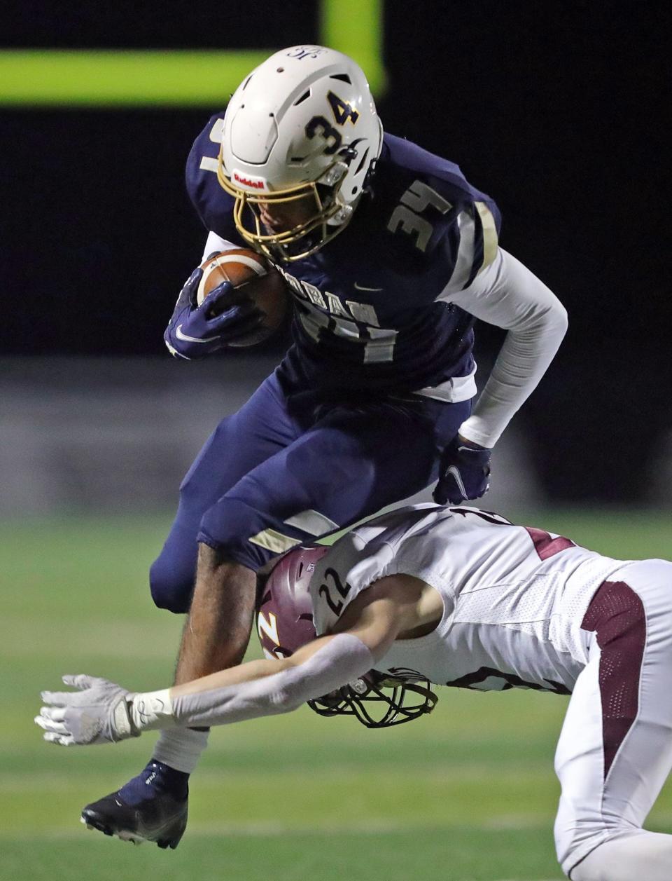 Hoban running back Markim McKinnie jumps over Walsh Jesuit defensive back Charlie Klug during the first half of a Division II regional championship football game, Friday, Nov. 19, 2021, in Twinsburg, Ohio.