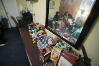Ida Cartlidge, center, and her sons Jakavien, left, Amarii, right, and Nolan are reflected in a mirror above their makeshift pantry of dry goods on Nov. 29, 2023, in the middle of their two-bed motel room that serves as their temporary residence after a deadly tornado destroyed their home in March. The Cartlidge family of five spent nearly a year in the cramped motel room in search of a more permanent home, like many of their displaced neighbors. (AP Photo/Rogelio V. Solis)