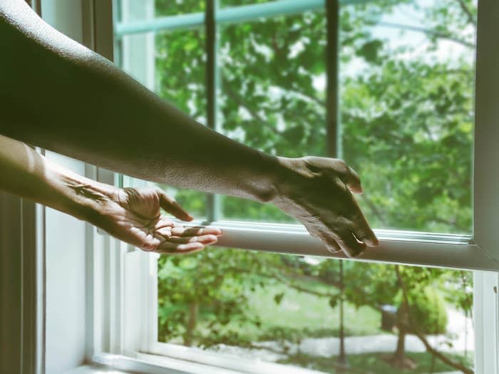 A woman opening a window.