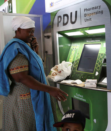 Rebecca Palai speaks on the phone with a consultant as she withdraws her medication at an ATM pharmacy which allows patients with chronic illnesses to receive repeat medication within three minutes, in Alexander township, South Africa, March 15, 2018. REUTERS/Siphiwe Sibeko