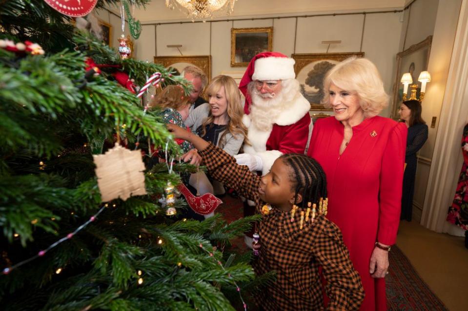 <p>For her first holiday season as Queen Consort, Camilla got some help decorating the Clarence House Christmas tree from Santa and a group of children helped by charities she supports.</p>