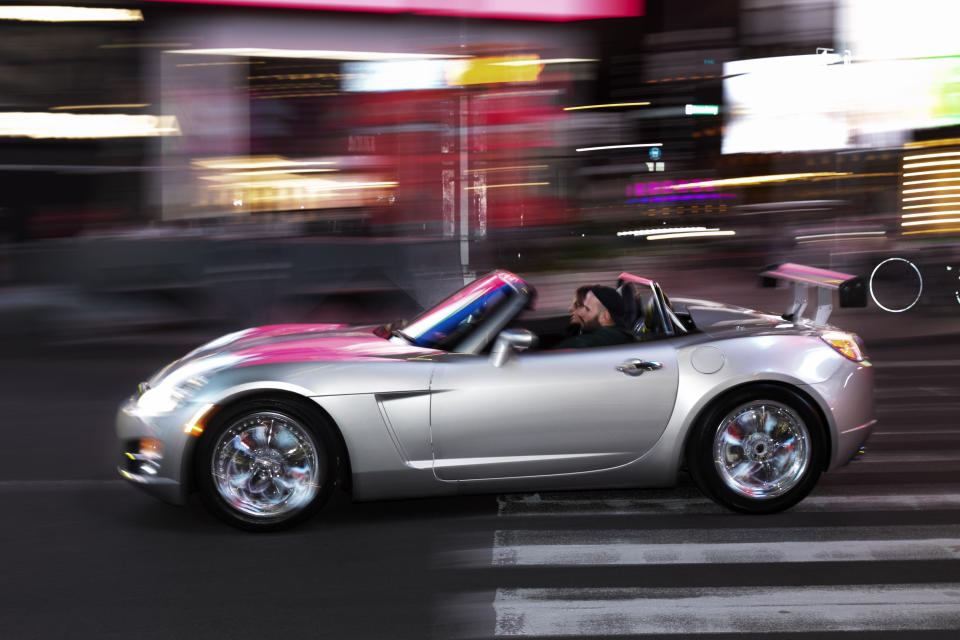 In this Saturday, May 2, 2020 photo, a man drives his convertible sports car through New York's Times Square. Times Square has taken a turn toward Tokyo Drift, with car-loving New Yorkers flocking to the theater district left empty by stay-at-home orders in the city seized by the coronavirus outbreak. (AP Photo/Mark Lennihan)