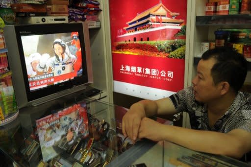 A shop owner watches television in Shanghai as China's first female astronaut Liu Yang is shown getting out of the return capsule of the Shenzhou-9 spacecraft after returning to earth on June 29, 2012. Three Chinese astronauts returned to Earth after achieving China's most complex and longest operations in orbit, major steps forward in the country's effort to build a space station