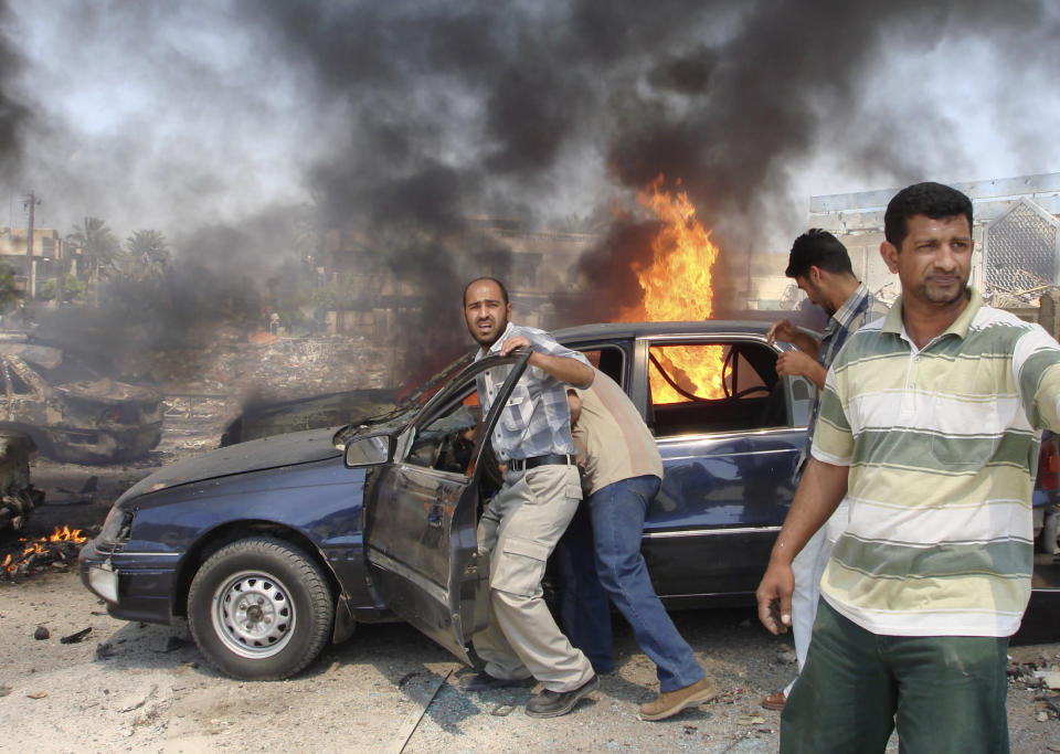 Men try to push a vehicle away from the scene of a suicide bomb attack in Baghdad, April 5, 2007. A Baghdad satellite television station run by Iraq's biggest Sunni political party briefly went off the air on Thursday after a suicide truck bomb exploded nearby, killing one person and wounding three. REUTERS/Stringer