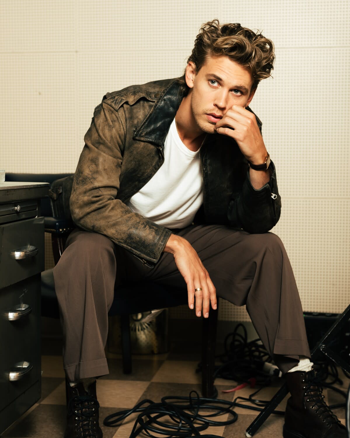 A man with blond hair poses in a leather jacket