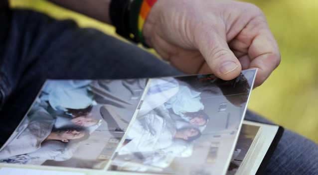 Rob Robertson, who wears a gay pride rainbow wristband, pages through a photo album of the final days of his son, Ryan, in Issaquah, Washington. Photo: AP