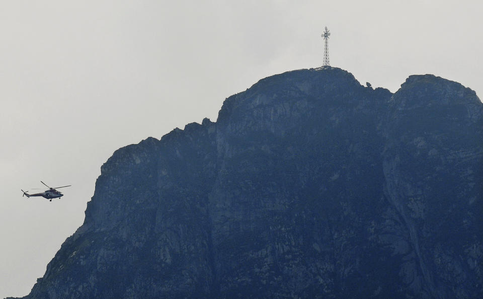 Rescuers in a helicopter checking the slopes of the Giewont peak for missing persons and anyone who might need help in the Tatra Mountains in Poland, Friday, Aug. 23, 2019. Three people are still missing in southern Poland after a deadly thunderstorm with multiple lightning strikes hit the Tatra Mountains, killing five people and injuring over 150. (AP Photo/Bartlomiej Jurecki)