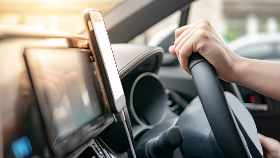 A person driving with a phone in a cradle.