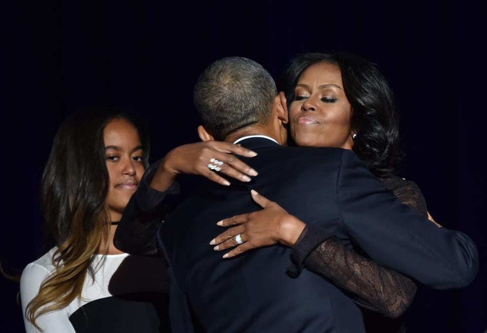 Michelle Obama hugs President Obama as daughter Malia looks on.