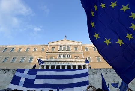 Protesters wave a Greek flag (L) at the entrance of the parliament building during a rally calling on the government to clinch a deal with its international creditors and secure Greece's future in the Eurozone, in Athens, Greece, June 22, 2015. REUTERS/Yannis Behrakis
