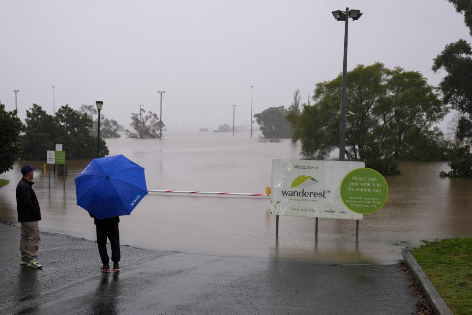 Residents look over flooded sports field at Richmond on the outskirts of Sydney, Australia, Tuesday, July 5, 2022. Hundreds of homes have been inundated in and around Australia's largest city in a flood emergency that was threatening 45,000 people, officials said on Tuesday. (AP Photo/Mark Baker)