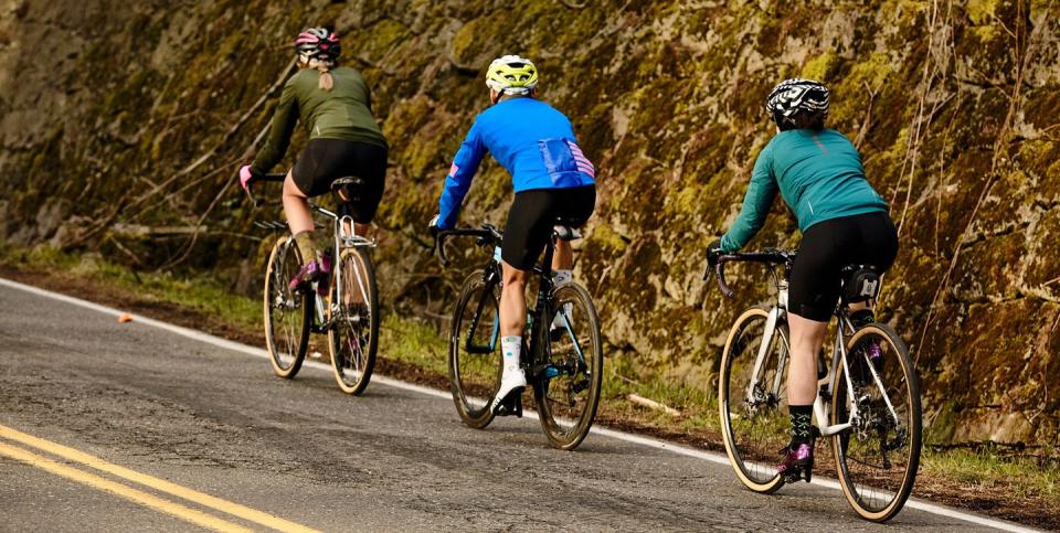three cyclists riding uphill alongside a mountain