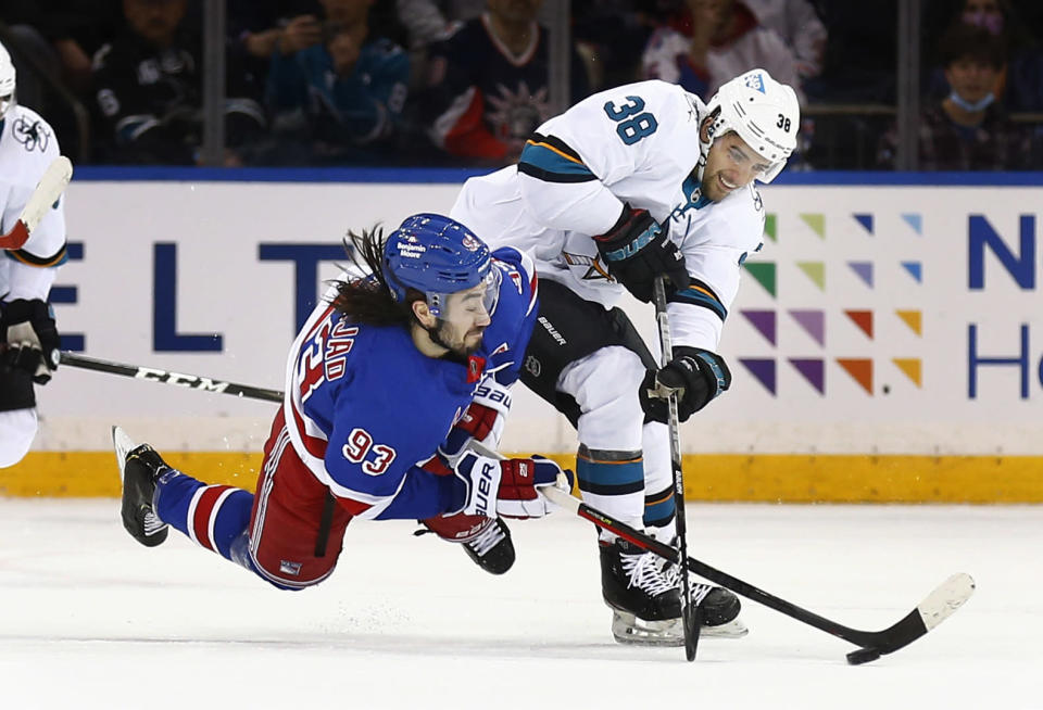 New York Rangers' Mike Zibanejad (93) and San Jose Sharks' Mario Ferraro (38) battle for the puck during the first period of an NHL hockey game Friday, Dec. 3, 2021, in New York. (AP Photo/John Munson)