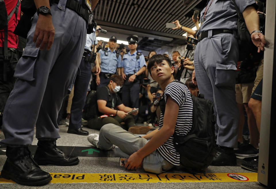 Two protesters are surrounded by police officers while sitting on the floor saying he is injured at a subway platform in Hong Kong Wednesday, July 24, 2019. Subway train service was disrupted during morning rush hour after dozens of protesters staged what they called a disobedience movement to protest over a Sunday mob attack at a subway station. (AP Photo/Vincent Yu)