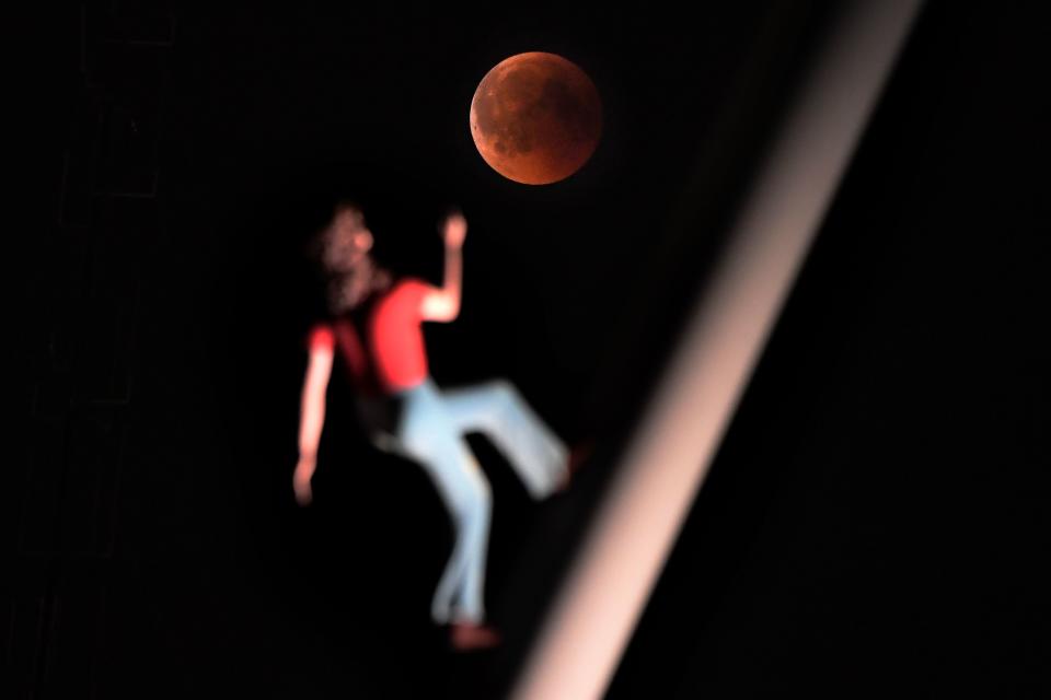 <p>A “blood moon” eclipse is pictured with a sculpture by the American artist Jonathan Borofsky “Woman walking to the sky” on July 27, 2018 in Strasbourg, eastern France. (Photo: Frederick Florin/AFP/Getty Images) </p>