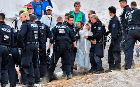 Police officers arrest climate activists after they entered the Garzweiler brown coal mine in Garzweiler, western Germany - Credit: &nbsp;INA FASSBENDER