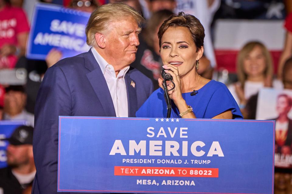 Gubernatorial candidate Kari Lake, flanked by former President Donald Trump, delivers remarks during Trump's rally at Legacy Sports Park in Mesa on Sunday, Oct. 9, 2022.
