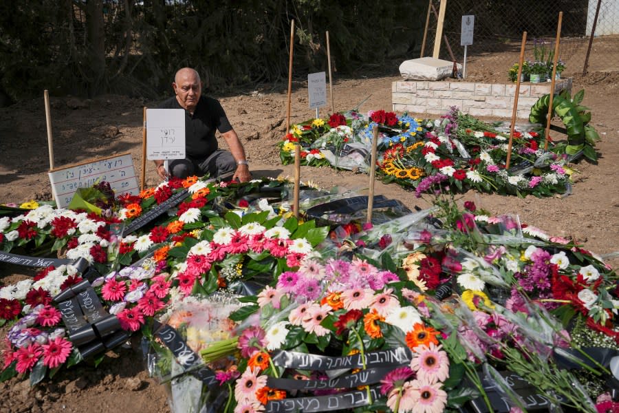 Following the death of Israeli news photographer Roy Edan and his wife Smadar, Edan’s father sits next to the couples’ graves during their funeral in Kfar Harif, Israel, Friday, Oct. 20, 2023. The couple was killed by Hamas militants in their house in Kibbutz Kfar Azza on Oct. 7, their 3-year-old daughter, Abigail, is believed to be held hostage in Gaza. (AP Photo/Tsafrir Abayov)