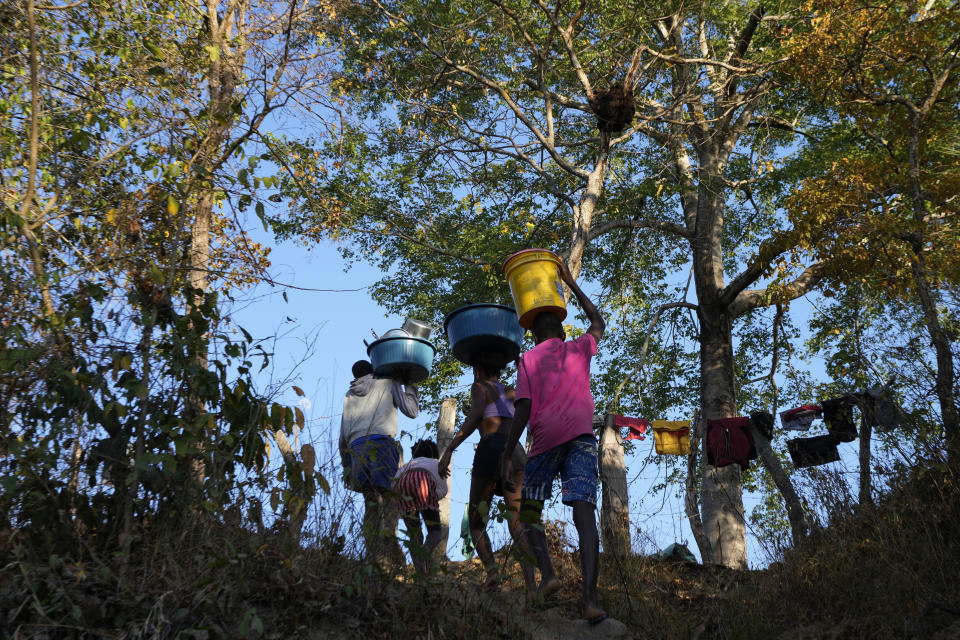 Children carry water from the Rio Branco at dawn at the Kalunga quilombo, in the rural area of Cavalcante in Goias state, Brazil, Monday, Aug. 15, 2022. The Kalunga quilombo villager´s ancestors settled there as runaway slaves more than 200 years ago. (AP Photo/Eraldo Peres)