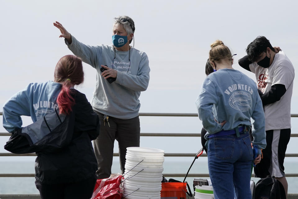 Lynn Adams, president of the Pacifica Beach Coalition, center, gives directions to volunteers before they clean areas near Sharp Park Beach in Pacifica, Calif., Wednesday, March 17, 2021. Disposable masks, gloves and other personal protective equipment have safeguarded untold lives during the pandemic. They’re also creating a worldwide environmental problem, littering streets and sending an influx of harmful plastic into landfills and oceans. (AP Photo/Jeff Chiu)