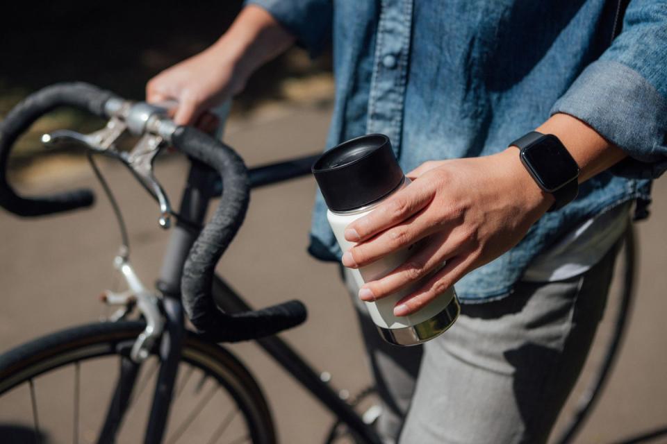 young man with a reusable coffee cup commuting by bike