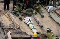 Firefighters lower a body from a building that was destroyed in Mexico City