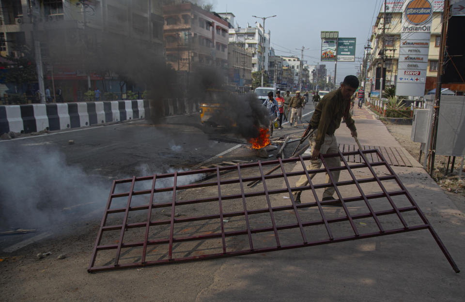 Police try to remove road blocks and douse fire set by protestors in Gauhati, India, Thursday, Dec. 12, 2019. Police arrested dozens of people and enforced curfew on Thursday in several districts in India’s northeastern Assam state where thousands protested legislation granting citizenship to non-Muslims who migrated from neighboring countries. (AP Photo/Anupam Nath)