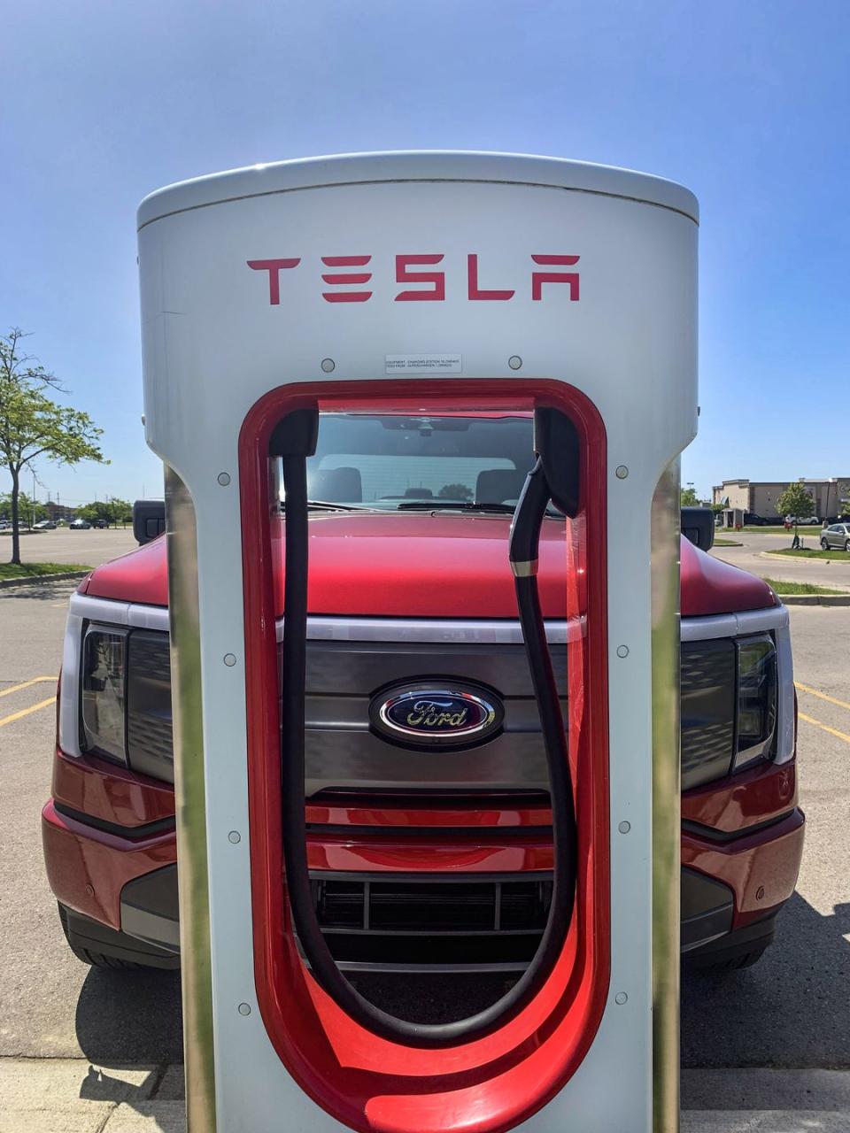 a ford f 150 lightning at a tesla charging station