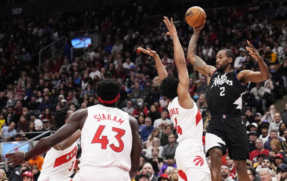 Los Angeles Clippers forward Kawhi Leonard (2) looks to pass around Toronto Raptors forward Scottie Barnes (4) as Raptors forward Pascal Siakam (43) watches during the first half of an NBA basketball game Tuesday, Dec. 27, 2022, in Toronto. (Frank Gunn/The Canadian Press via AP)