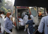 Health workers prepare to take out bodies of six victims of COVID-19 from an ambulance for cremation in New Delhi, India, Monday, April 19, 2021. India has been overwhelmed by hundreds of thousands of new coronavirus cases daily, bringing pain, fear and agony to many lives as lockdowns have been placed in Delhi and other cities around the country. (AP Photo/Manish Swarup)