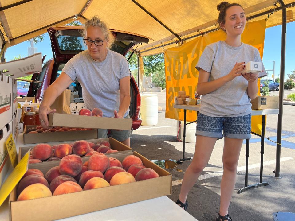 Karen Carr, left, places a box of peaches on a table while Maegen Carr talks to a customer at the Debbie's Palisade Peaches stand at Bath Garden and Nursery, 2000 E. Prospect Road, Fort Collins, Colo., on Tuesday, Aug. 23, 2022.